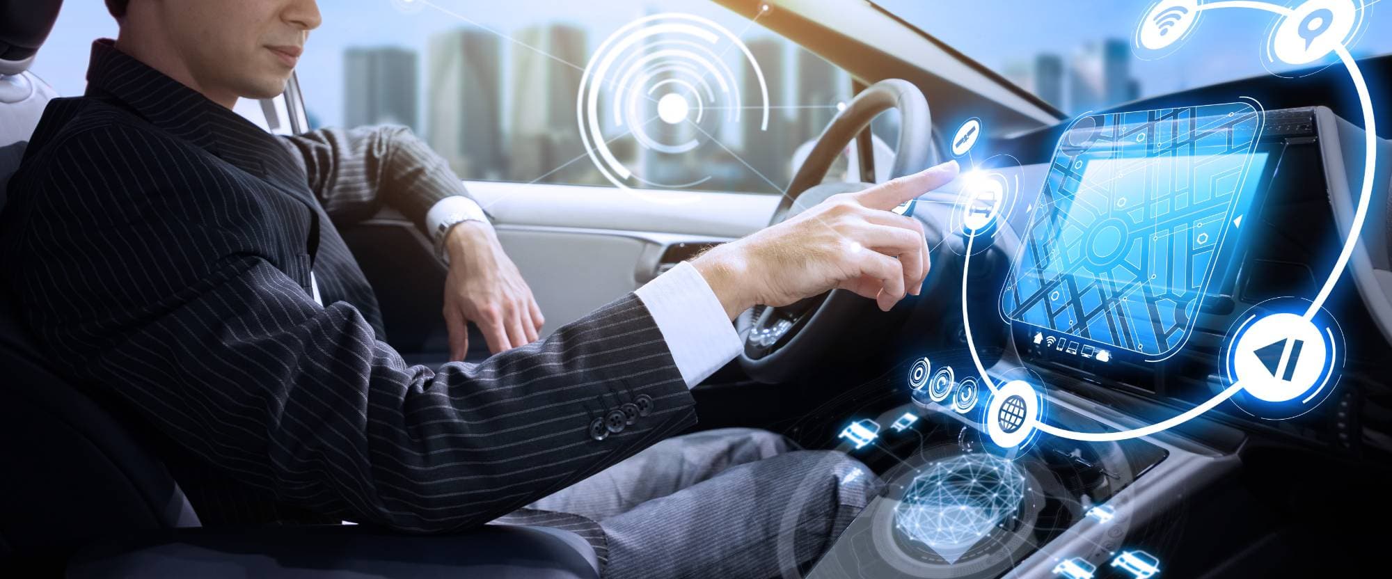 A man in a suit sits in a modern car, interacting with a large touchscreen dashboard displaying navigation and futuristic digital interface graphics.