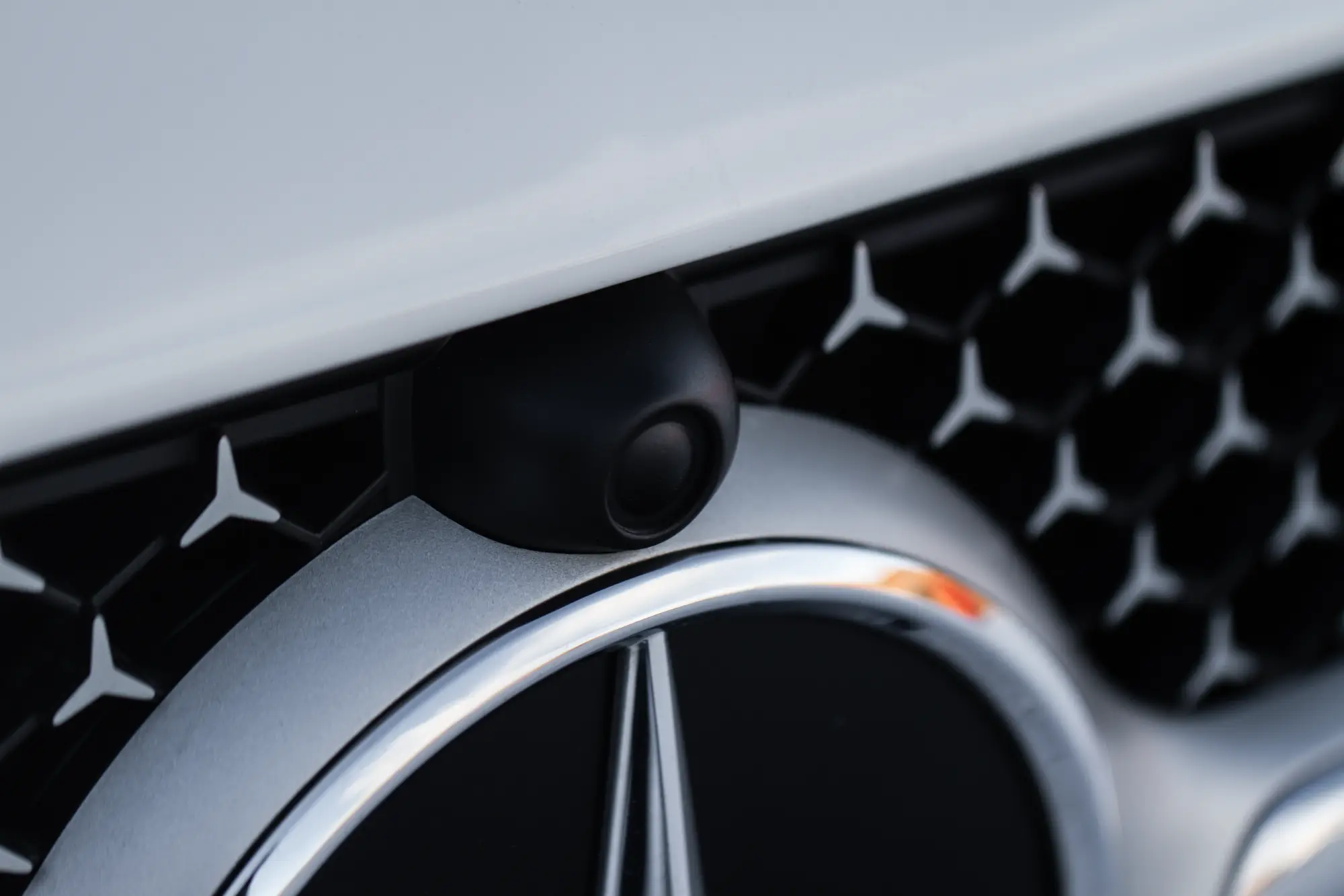 Close-up of the front section of a car, showing detailed features such as the grille, headlights, and body contours, with reflections highlighting the paint finish.